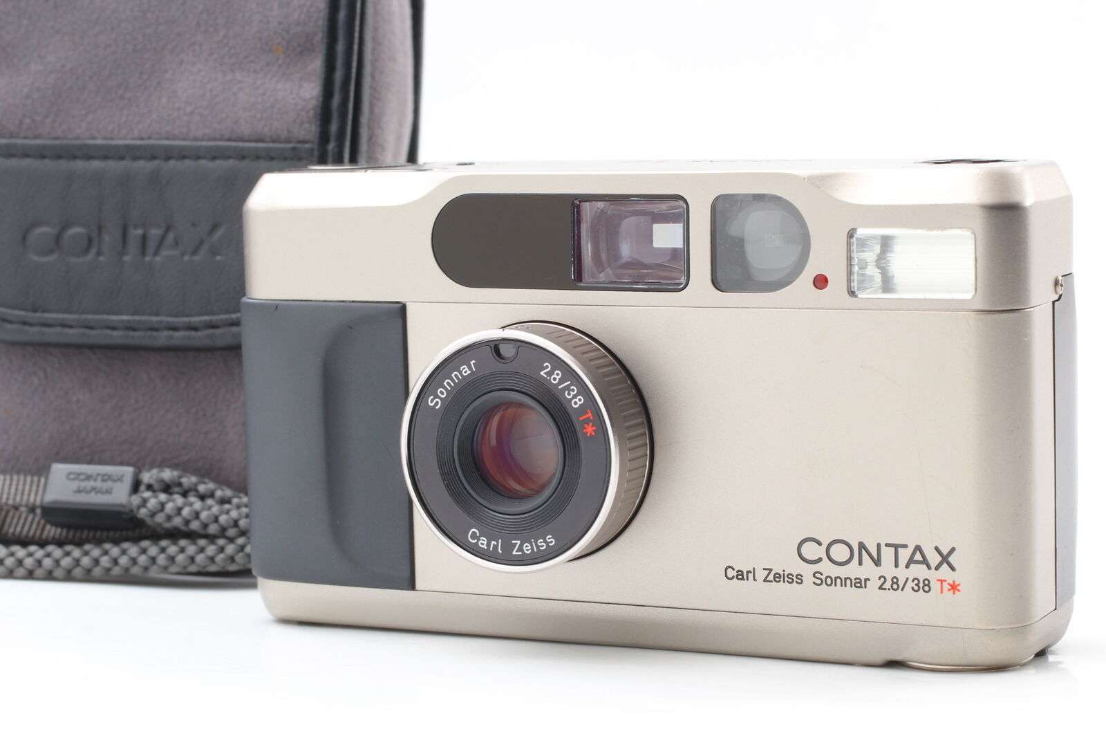 A Contax T2 35mm film camera with Carl Zeiss Sonnar lens, displayed in front of its carrying case.