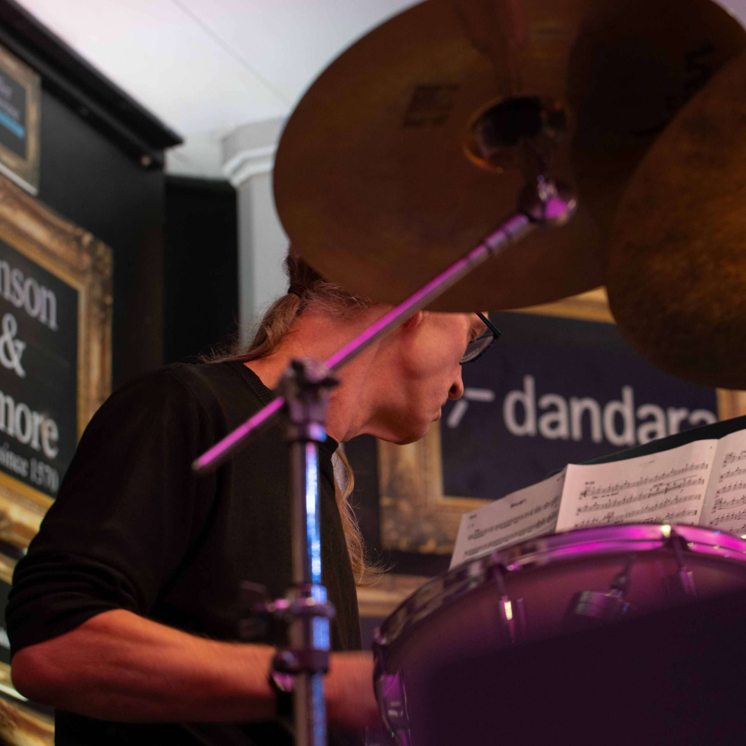 A person playing drums and reading sheet music during a live music performance
