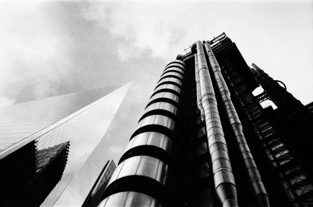 Black and white photo of towering skyscrapers with exposed structural elements against a cloudy sky