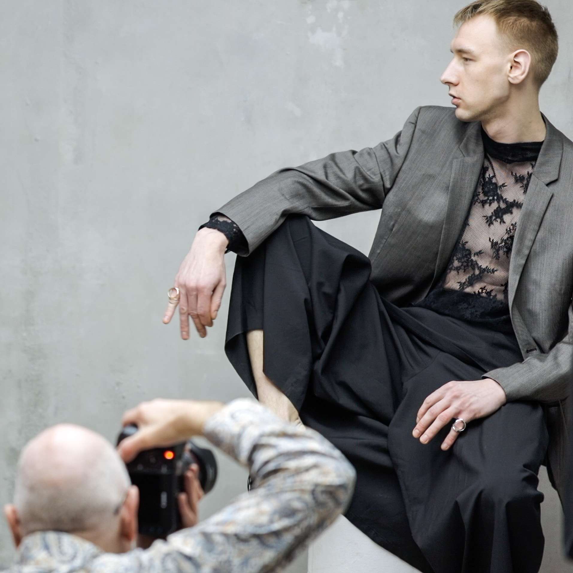 A photographer capturing a male model in stylish attire against a textured backdrop