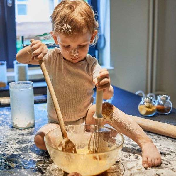 boy getting messy while trying to mix a cake